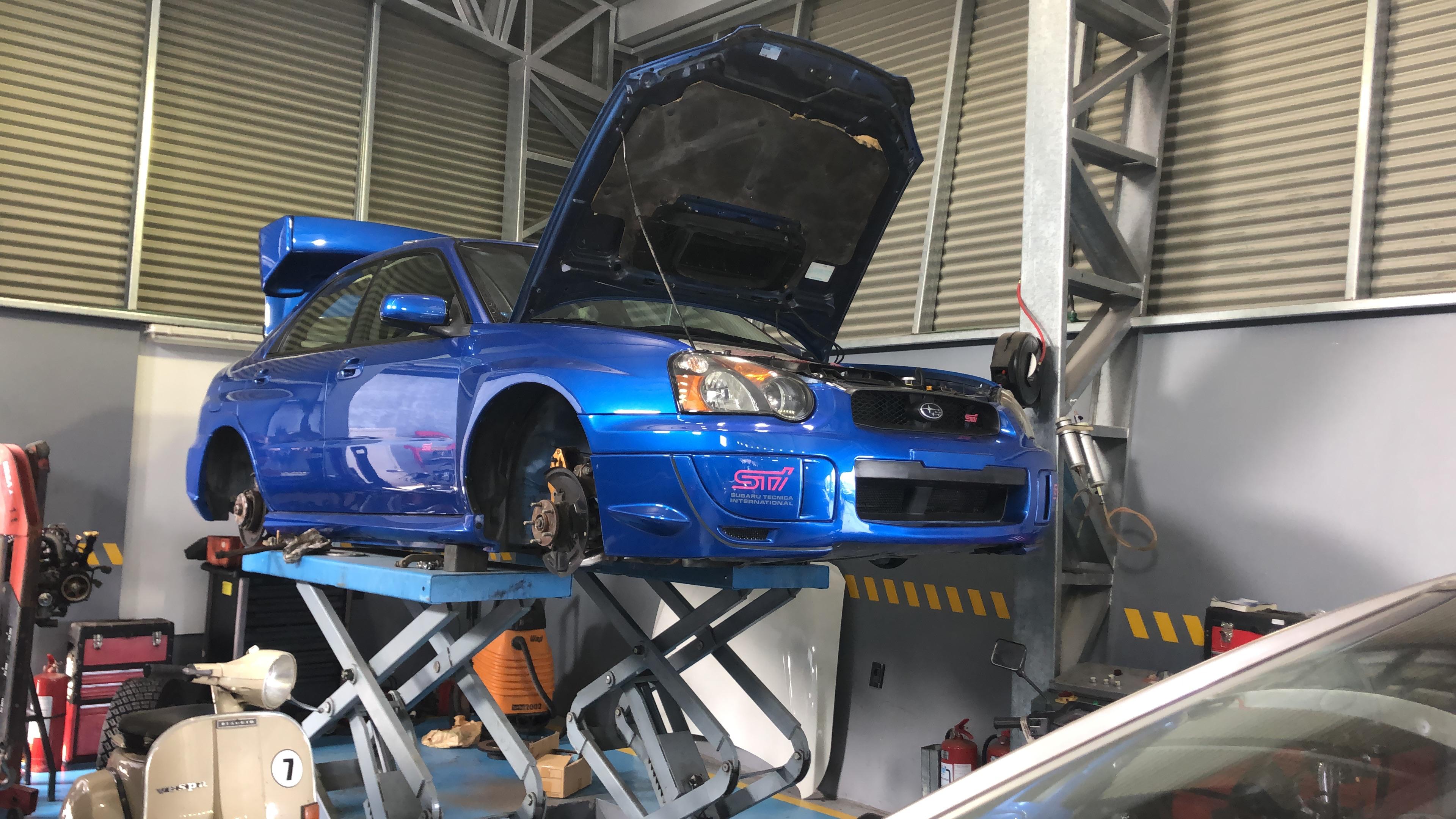 Subaru azul elevado para una revisión en el taller