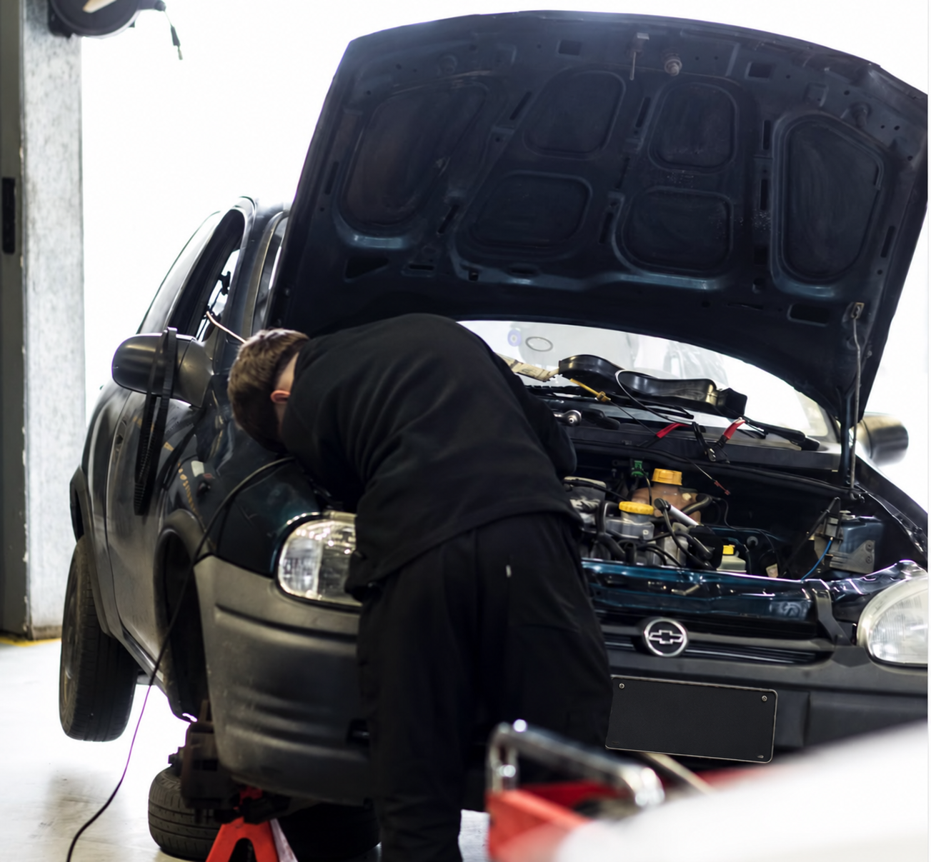 Mecánico revisando el sistema eléctrico de un Chevrolet Corsa en el taller