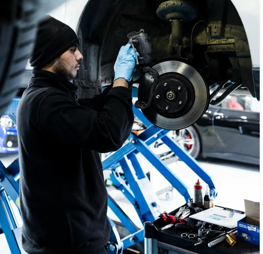 Mecánico inspeccionando los frenos de un vehículo elevado